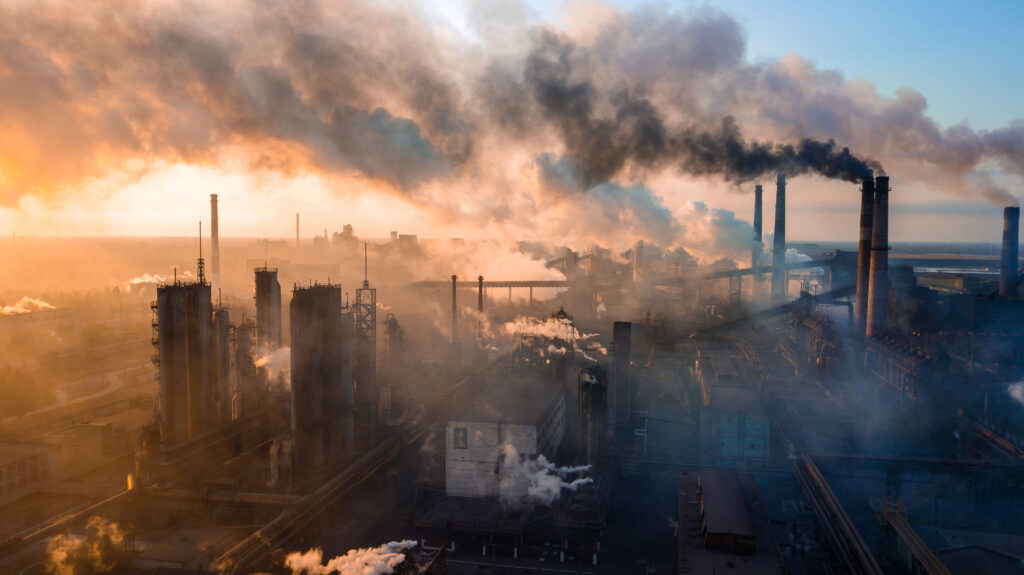 drone view of factory producing large amounts of smoke from chimneys