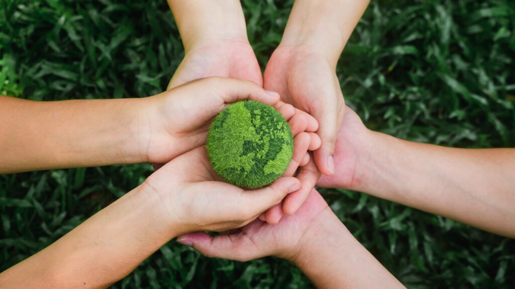 4 people holding a green earth in their hands